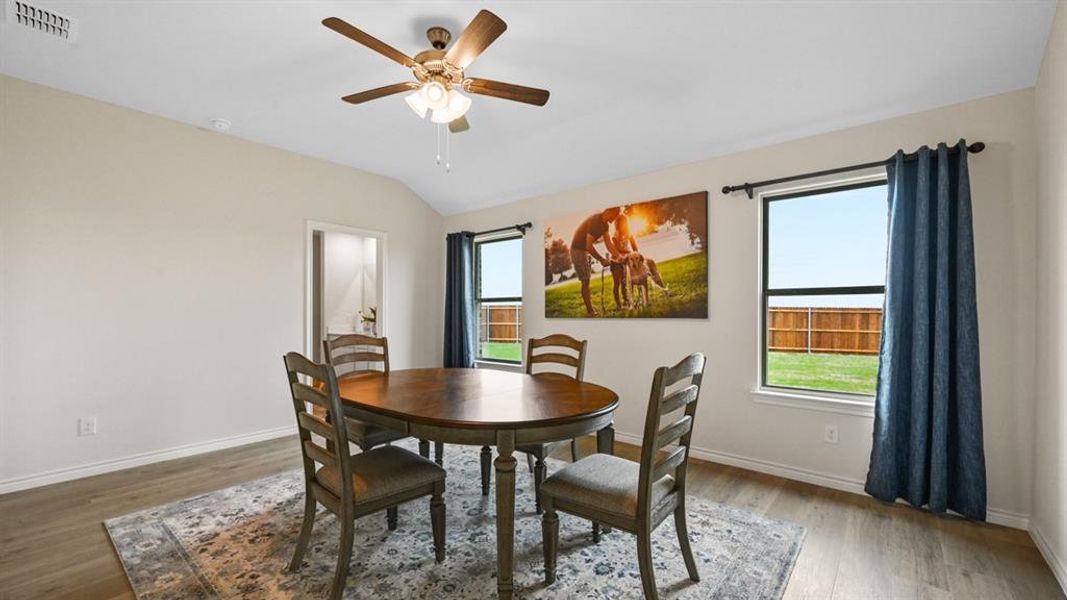 Dining space with healthy amount of natural light, light wood-style flooring, a ceiling fan, and vaulted ceiling Dining space with healthy amount of natural light, light wood-style flooring, a ceiling fan, and vaulted ceiling