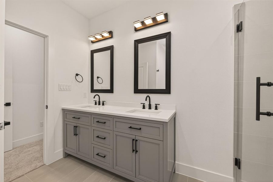This bathroom features a modern double vanity with sleek black fixtures, framed mirrors, and ample storage. The neutral tones and contemporary lighting create a bright, clean, and stylish atmosphere. This bathroom features a modern double vanity with sleek black fixtures, framed mirrors, and ample storage. The neutral tones and contemporary lighting create a bright, clean, and stylish atmosphere.