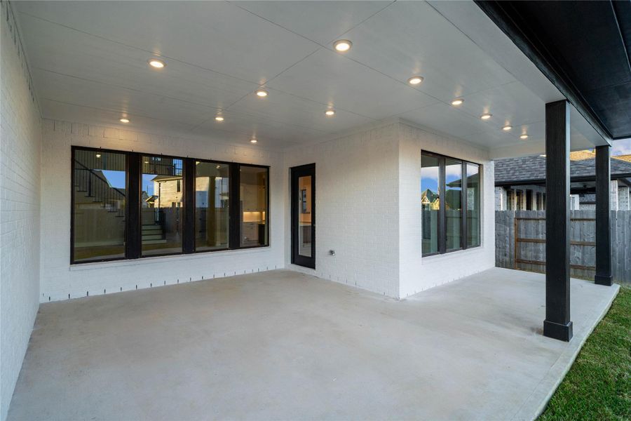 Step outside to a generously sized covered rear patio, the perfect extension of your indoor living space for year-round enjoyment. The patio features sleek concrete flooring and recessed lighting, creating a bright and inviting atmosphere.
