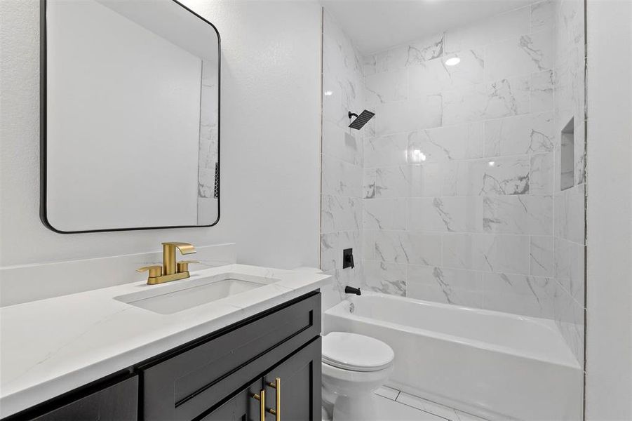 Full bathroom featuring toilet, tiled shower / bath combo, vanity, and tile patterned floors