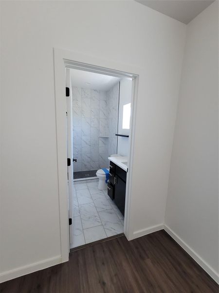 Step into a new primary bathroom featuring sleek tile and a functional vanity.