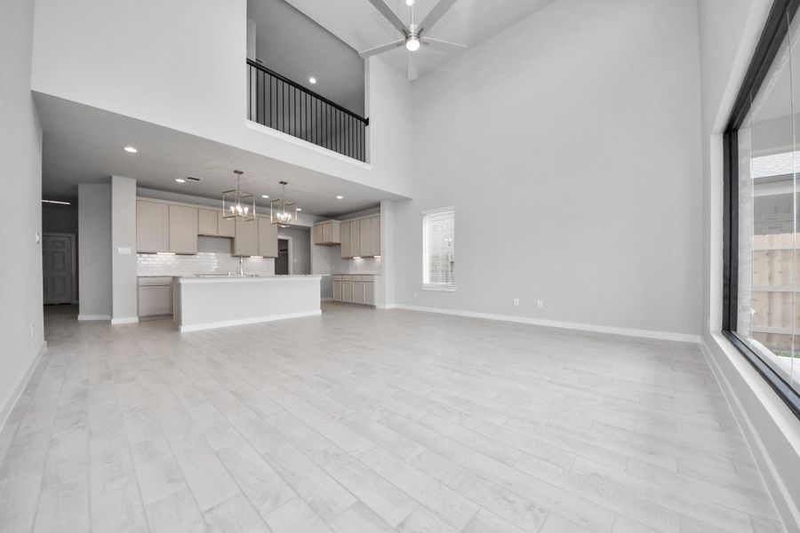 Gather the family and guests together in your lovely living room! Featuring soaring high ceilings, recessed lighting, ceiling fan, custom paint, gorgeous floors, and large windows that provide plenty of natural lighting throughout the day. Sample photo of completed home with similar floor plan. Actual colors and selections may vary.