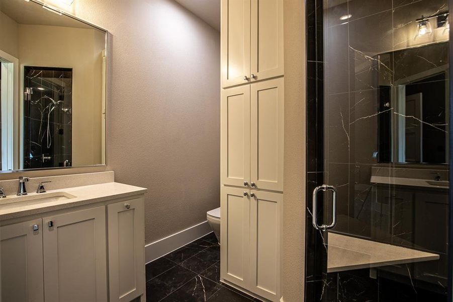 Bathroom with a shower with shower door, vanity, tile patterned flooring, and toilet