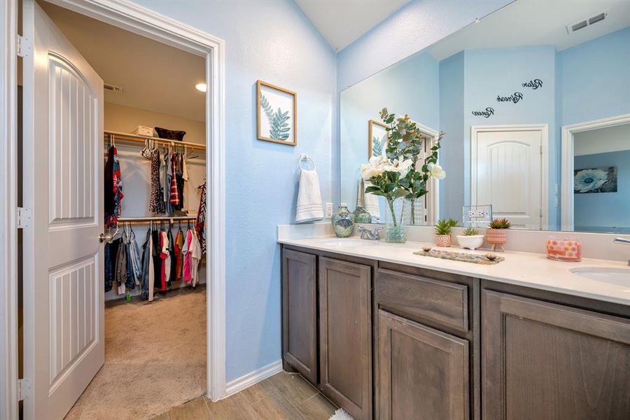 Bathroom featuring double vanity, light wood finished floors, and a walk in closet