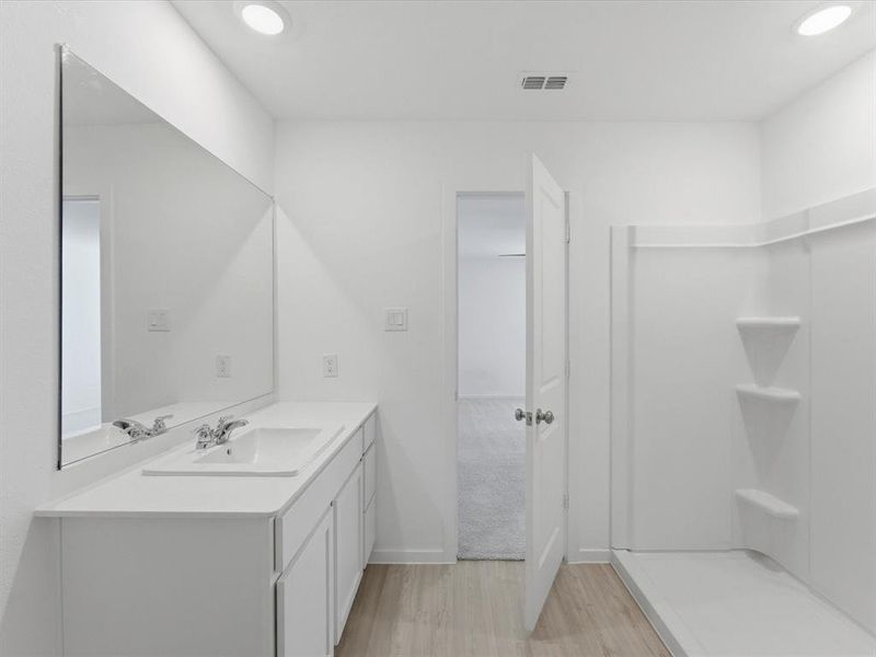 Bathroom featuring a single vanity with an integrated sink, polished chrome faucet, and a large wall-mounted mirror