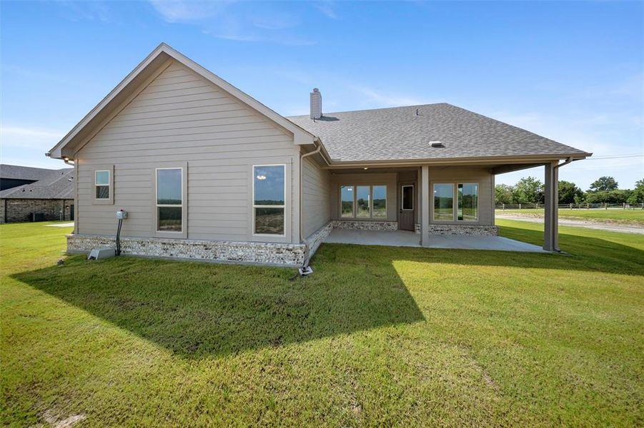 Back of house with a patio, a shingled roof, a lawn, and a chimney Back of house with a patio, a shingled roof, a lawn, and a chimney