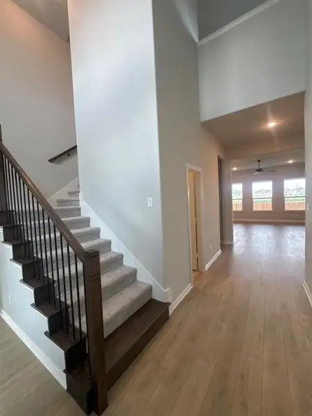 Two-story foyer featuring a carpeted staircase with dark wood treads and wrought iron balusters