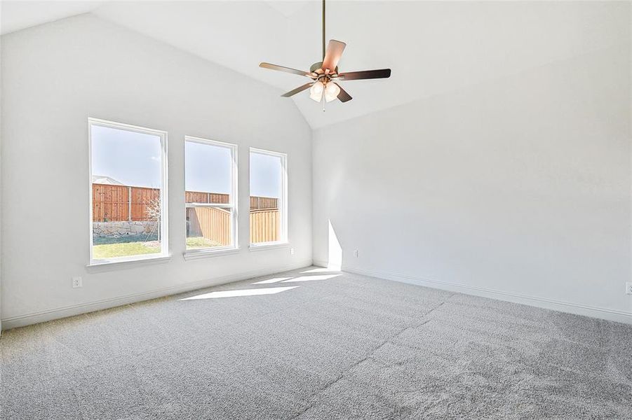 Spare room with light colored carpet, ceiling fan, and vaulted ceiling