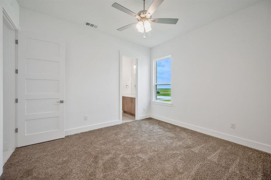 Empty room with light colored carpet, baseboards, visible vents, and ceiling fan Empty room with light colored carpet, baseboards, visible vents, and ceiling fan