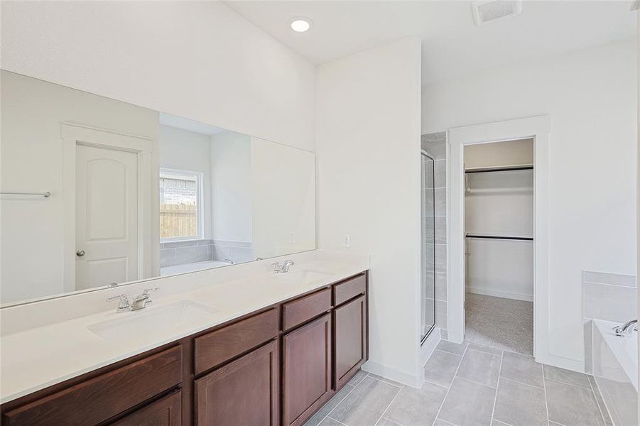 Bathroom featuring tile patterned floors, separate shower and tub, and vanity