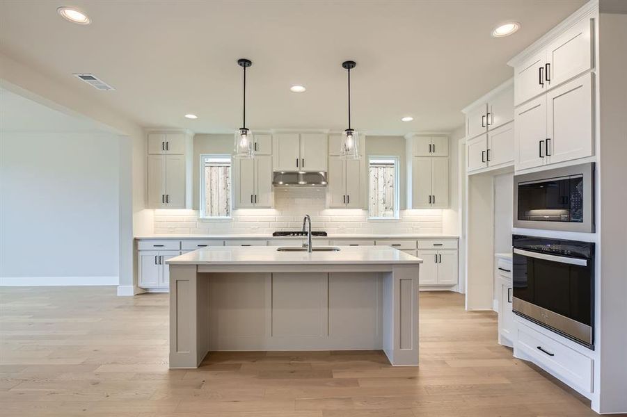 Kitchen with appliances with stainless steel finishes, tasteful backsplash, light countertops, light wood-style floors, and recessed lighting