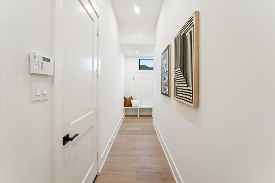 On the left side of the entrance foyer is the practical hallway leading to the garage entrance and mud room.  Around the corner under the stairway is even more space for storage, shelving or whatever is needed for organizing solutions.