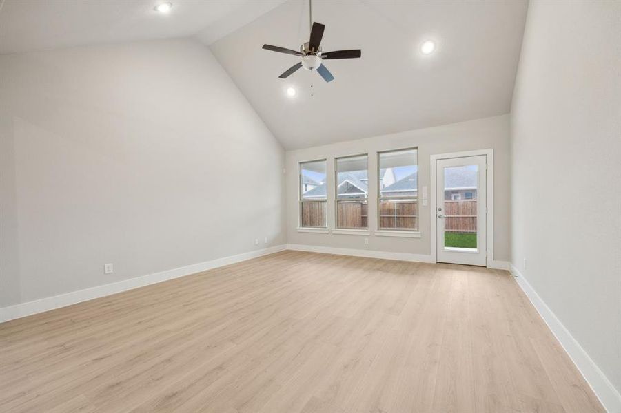 Spare room with ceiling fan, high vaulted ceiling, and light wood-type flooring