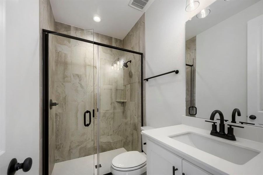 Bathroom featuring a glass-enclosed shower with black trim, tile surround, and a built-in shelf Bathroom featuring a glass-enclosed shower with black trim, tile surround, and a built-in shelf