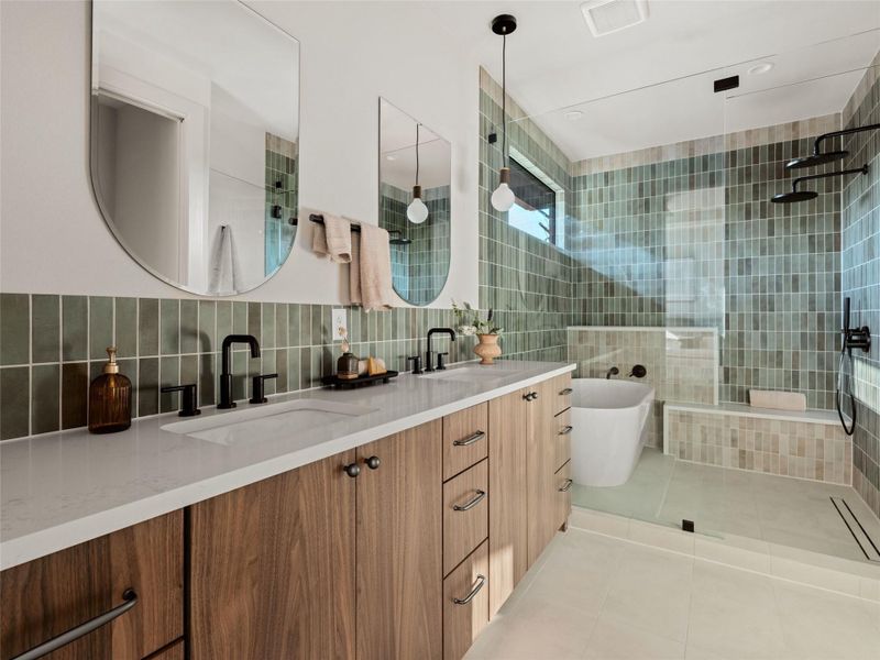 Bathroom with a freestanding bath, light tile patterned floors, tiled shower, double vanity, and tile walls