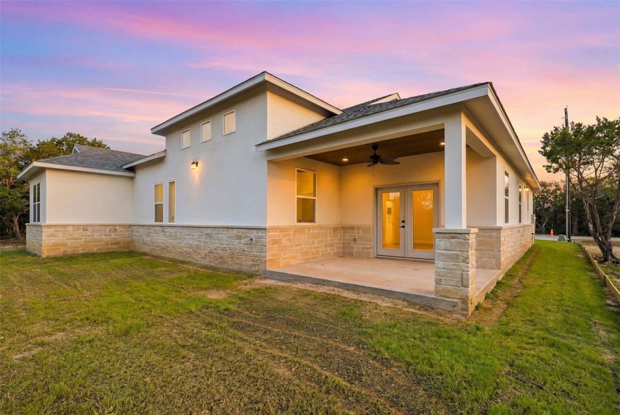 Rear exterior featuring a covered patio with a ceiling fan, recessed lighting, and stone columns Rear exterior featuring a covered patio with a ceiling fan, recessed lighting, and stone columns