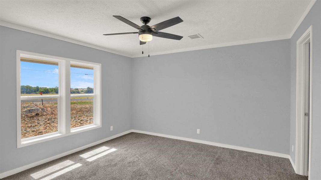 Plush carpeting and wide windows framing neighborhood views define this tranquil bedroom space.