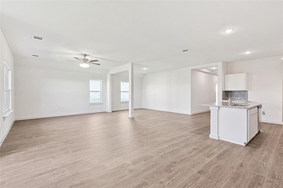 Unfurnished living room featuring light wood-type flooring, sink, and ceiling fan