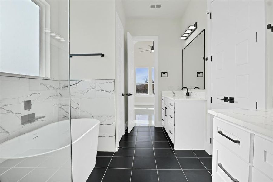 Bathroom with tile walls, a bath, tile patterned flooring, and vanity