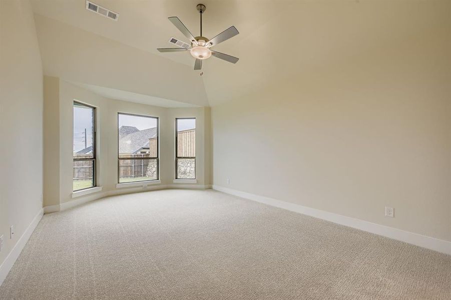 Empty room featuring light colored carpet, ceiling fan, and high vaulted ceiling