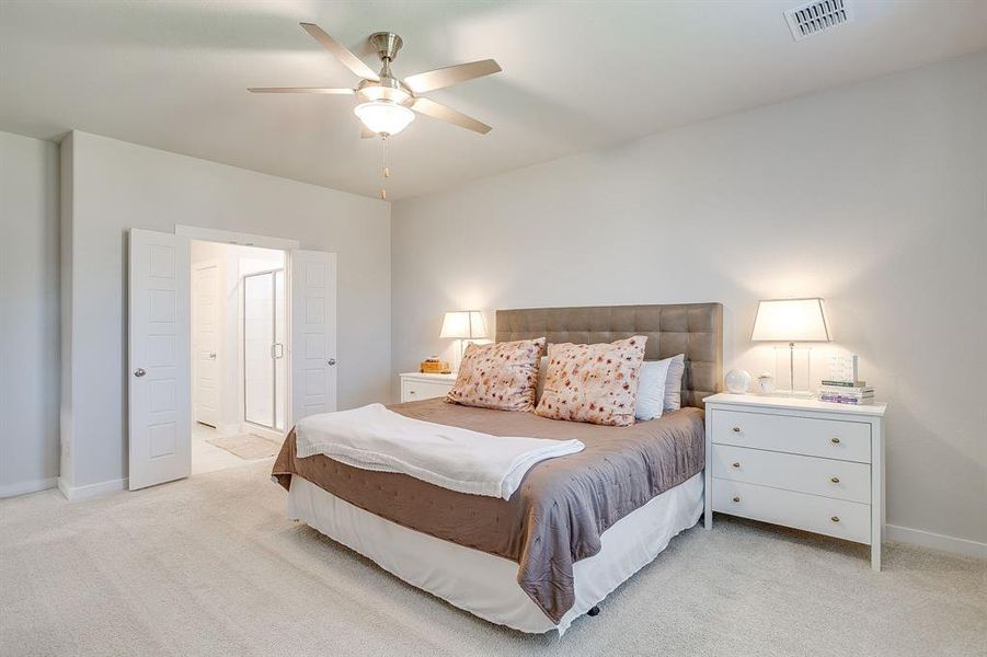 Bedroom with light colored carpet, a ceiling fan, and ensuite bathroom Bedroom with light colored carpet, a ceiling fan, and ensuite bathroom