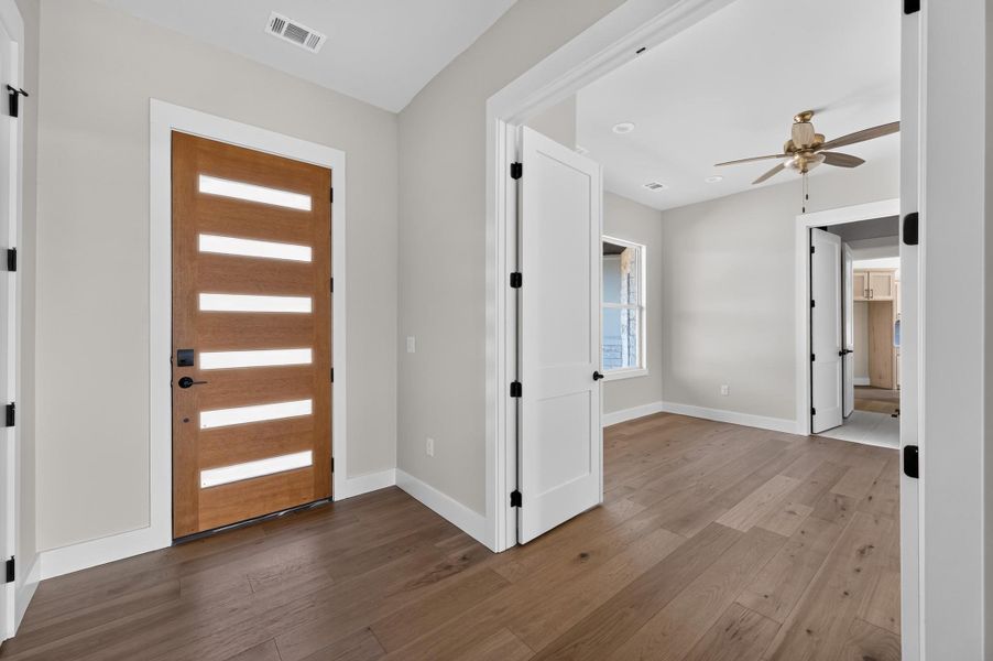 Gleaming hardwood floors and a modern glass-paneled entry door define this inviting foyer space.
