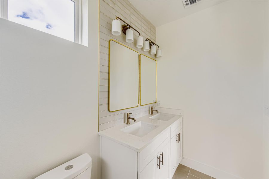 Bathroom featuring double vanity and light tile patterned floors Bathroom featuring double vanity and light tile patterned floors