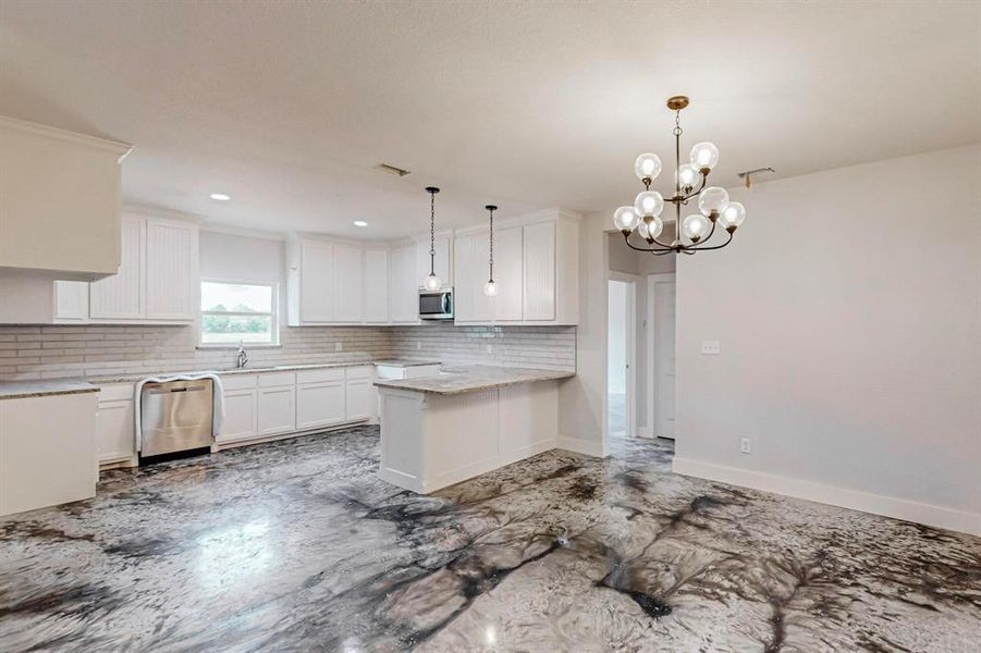 Kitchen featuring a notable chandelier, white cabinets, sink, decorative light fixtures, and stainless steel appliances