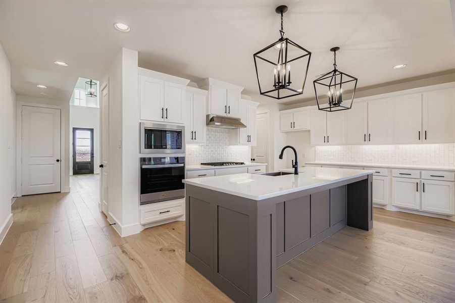 Kitchen with white cabinetry, a center island with sink, appliances with stainless steel finishes, recessed lighting, and pendant lighting
