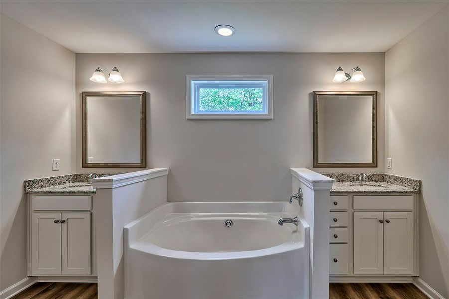 This serene bath features a soaking tub, dual vani
