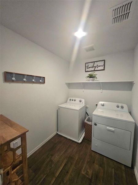 Dedicated utility space featuring wood-finish flooring, white walls, and a ceiling-mounted light fixture