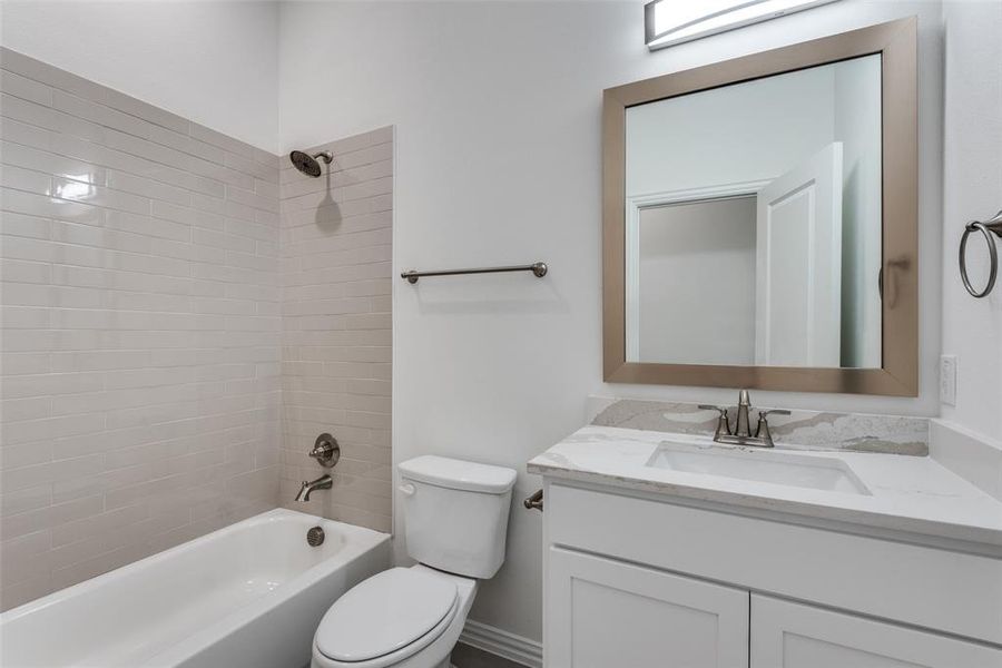 Full bathroom with vanity, tiled shower / bath combo, and toilet