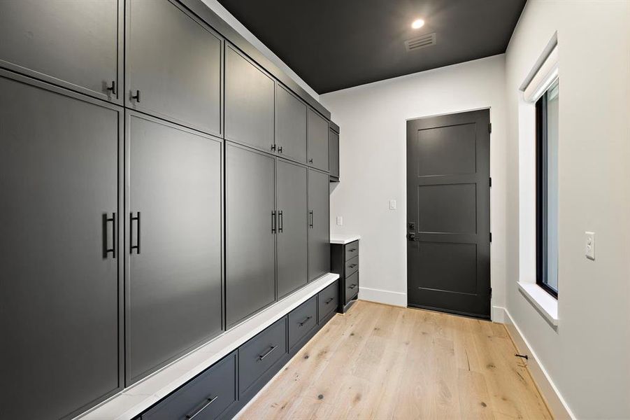 Modern Skinny Shaker-Style Custom Cabinets in White Oak Rift Cut finish, SherwinWilliams Green Black, and Black Metal Doors. Cabinets feature built-in organization