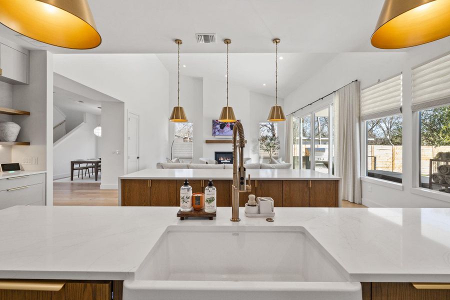 Kitchen with pendant lighting, light stone counters, lofted ceiling, open floor plan, and open shelves