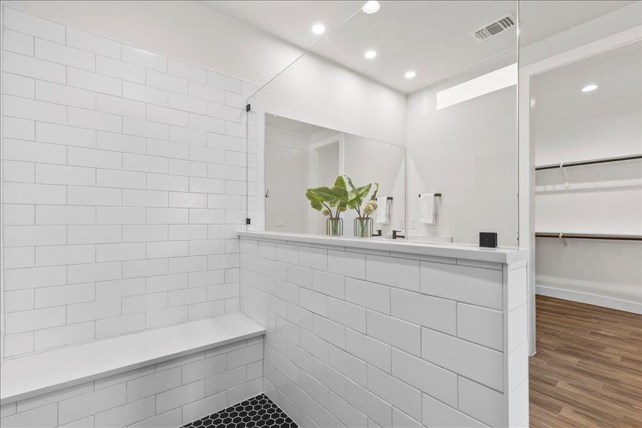 Bathroom with recessed lighting, wood finished floors, a spacious closet, and walk in shower