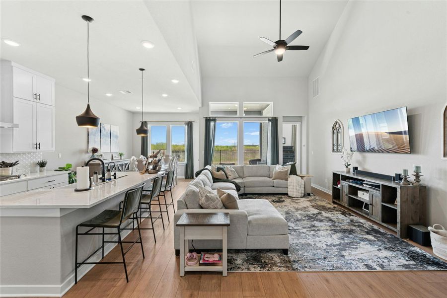 Open Living room with a lighted ceiling fan, plenty of natural light, a high ceiling, and recessed lighting