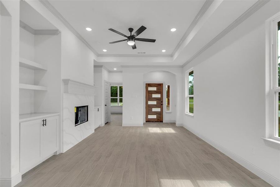 Unfurnished living room featuring plenty of natural light, a ceiling fan, recessed lighting, a fireplace, and light wood finished floors Unfurnished living room featuring plenty of natural light, a ceiling fan, recessed lighting, a fireplace, and light wood finished floors