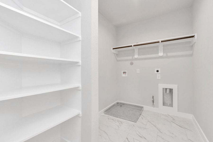A perfect blend of functionality and comfort. Laundry room, thoughtfully equipped with shelving for effortless organization. Both gas and electric connections available. Sample photo of completed home with similar floor plan. Actual colors and selections may vary.