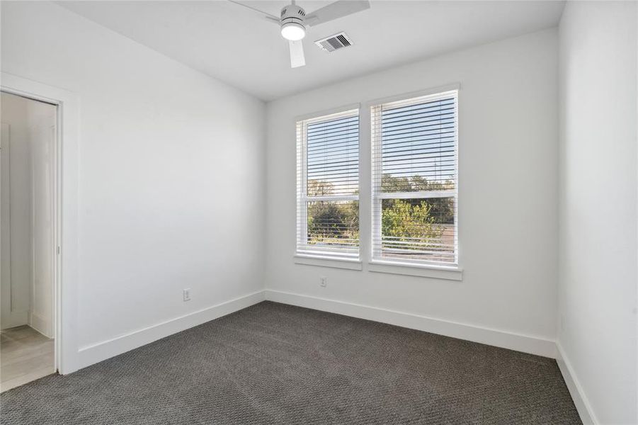 Secondary bedroom featuring a ceiling fan for added comfort and large windows that flood the space with natural light, creating a bright and welcoming atmosphere.