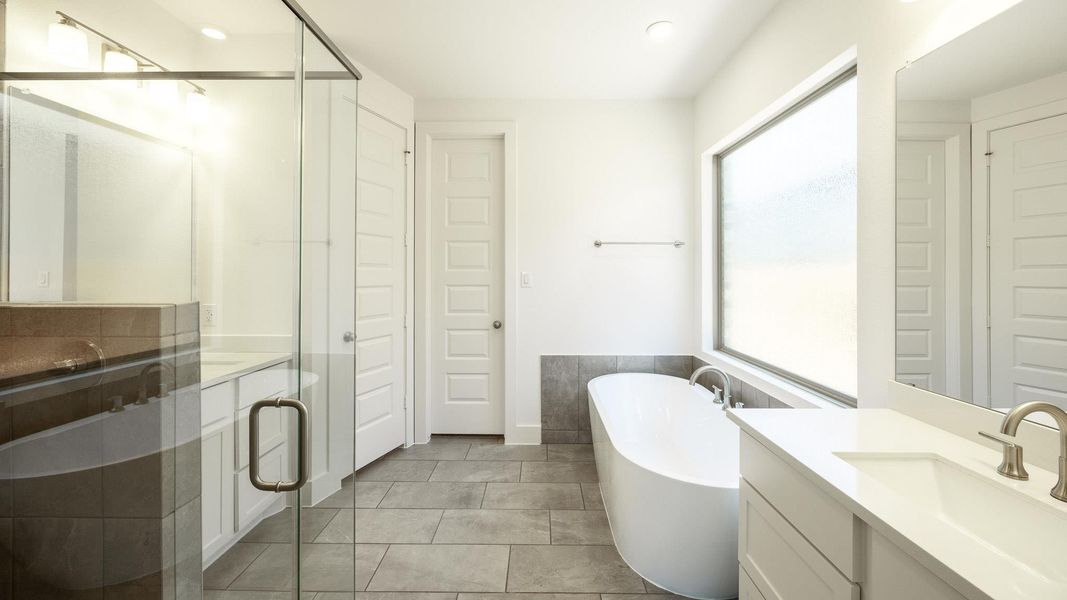 Full bathroom with two vanities, a freestanding tub, a shower stall, tile patterned flooring, and recessed lighting Full bathroom with two vanities, a freestanding tub, a shower stall, tile patterned flooring, and recessed lighting