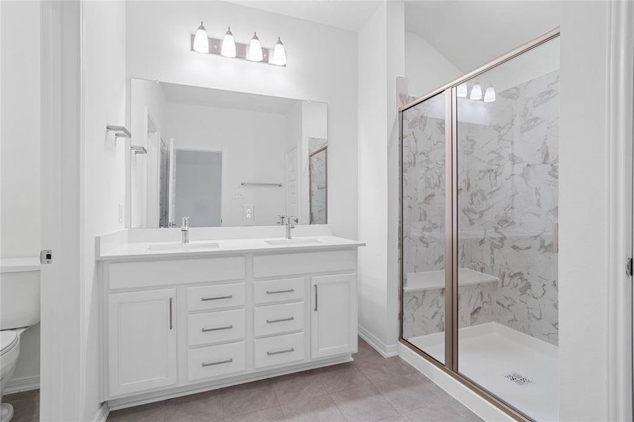 This primary bathroom is definitely move-in ready! Featuring an oversized walk-in shower with seat and tile surround, stained cabinets with dual vanities, high ceilings, custom paint, sleek and dark modern finishes.