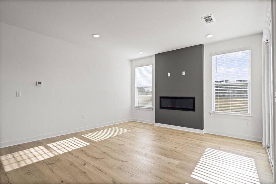Unfurnished living room with a large fireplace, light wood-style floors, and recessed lighting