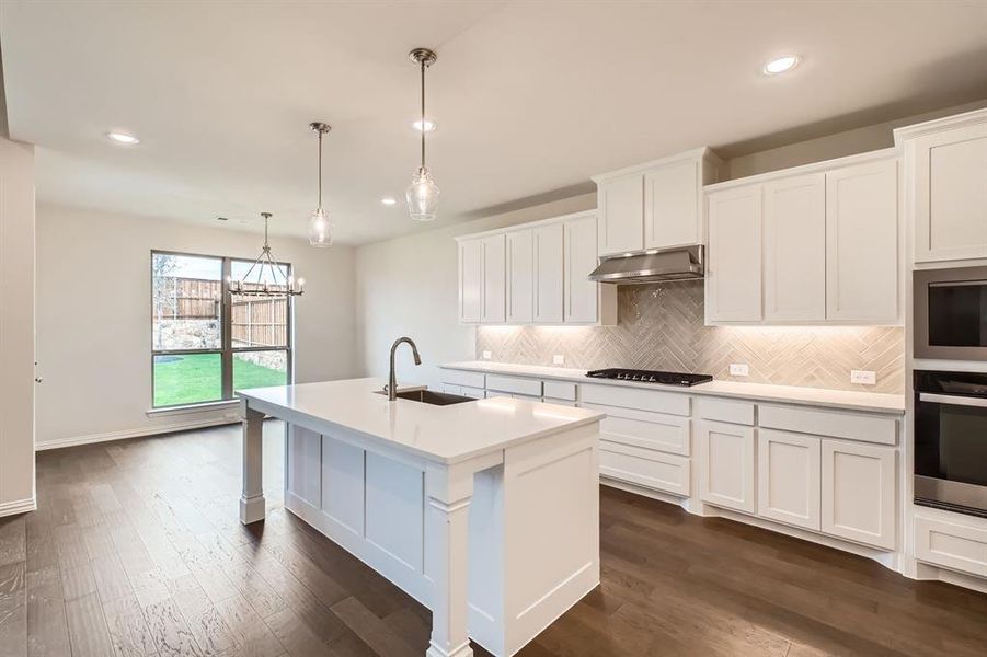 Kitchen featuring white cabinets, sink, a kitchen island with sink, pendant lighting, and appliances with stainless steel finishes