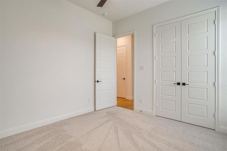 Unfurnished bedroom featuring light colored carpet, a closet, and ceiling fan