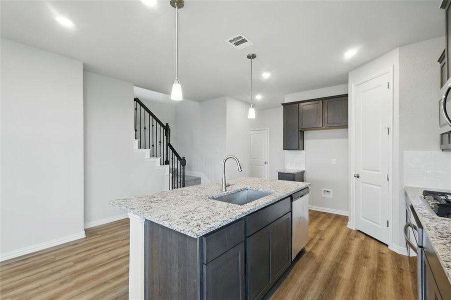 Kitchen with stainless steel appliances, light wood finished floors, a kitchen island with sink, light stone countertops, and recessed lighting Kitchen with stainless steel appliances, light wood finished floors, a kitchen island with sink, light stone countertops, and recessed lighting