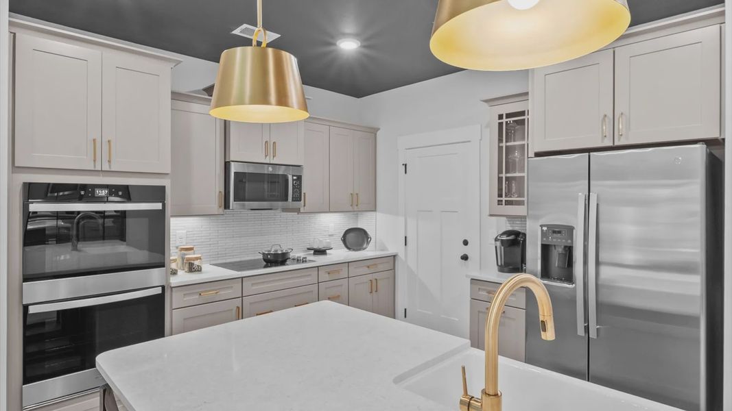 Exceptional kitchen featuring a spacious island, eye-catching pendant lights, and modern finishes at Barton Hollow