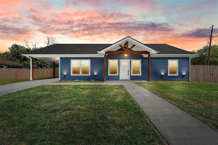 View of front facade featuring driveway, a shingled roof, and an attached carport