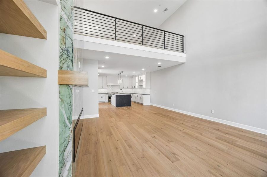 Unfurnished living room featuring a high ceiling, light wood-style floors, and recessed lighting Unfurnished living room featuring a high ceiling, light wood-style floors, and recessed lighting