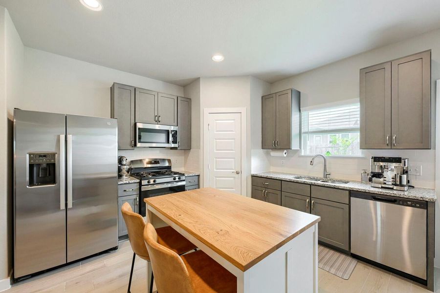 A contemporary kitchen showcasing stainless steel appliances, abundant cabinetry, and a central island with bar seating. A contemporary kitchen showcasing stainless steel appliances, abundant cabinetry, and a central island with bar seating.