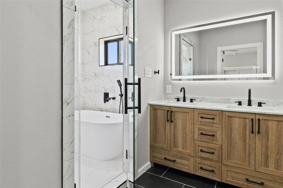 Spa-inspired primary bath featuring a fully tiled wet room with a freestanding soaking tub, dual shower heads, double vanities, illuminated mirror, and a private water closet. Thoughtfully designed with both style and functionality in mind.
